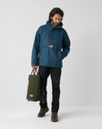 Man wearing a blue jacket holding a green bag on a white background