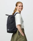 Person wearing a black backpack on a plain background