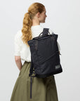 Person wearing a black backpack on a plain background