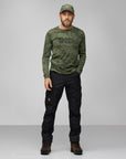 man wearing green long sleeve top with Fjällräven logo and black trekking trousers