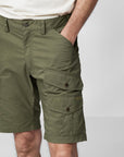 putting hand into pockets of a green bermudas shorts