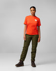 woman wearing orange round neck t-shirt with arctic fox logo and brown pants