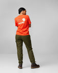 woman wearing orange round neck t-shirt with arctic fox logo and brown pants