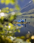 A tent by a lake with mountains in the background