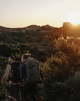 a couple carrying trekking backpacks and trekking in the highlands