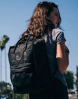 woman carrying kanken black backpack on the street