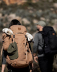 Two hikers with backpacks walking through a rocky landscape.