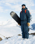 Person in winter gear holding a snowboard on a snowy mountain