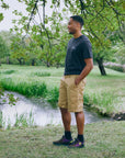 Man standing in a park by a stream with trees and grass in the background