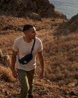 man wearing grey melange round neck t-shirt walking up a grass terrain