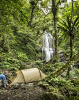 camping tent set up near the waterfall in a forest