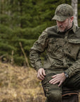 Man in camouflage clothing sitting in a forest