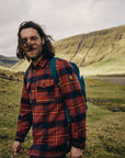 man wearing autumn leaf-dark navy long sleeve shirt walking along a grass terrain