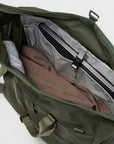 Green duffel bag with a laptop and jacket inside on a white background