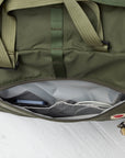 Green duffel bag with a key and phone inside on a white background