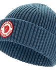 Blue knit beanie with Fjällräven logo on a white background