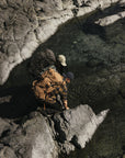 Two people with backpacks standing on rocky terrain near a body of water.