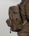 Person wearing a large brown backpack on a plain background