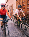 Two cyclists riding bicycles on a cobblestone street with wooden doors in the background.