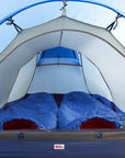 Camping tent with two sleeping bags inside, set against a clear blue sky.
