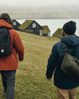 two men carrying bags hiking on a mountain