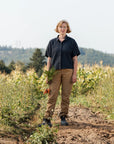 Person standing in a field holding carrots with a natural background