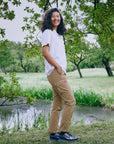 Person standing in a park with trees and a pond in the background