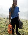 woman wearing blue round t-shirt carrying a backpack on grass surface