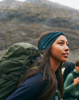 Two people hiking in a mountainous area with green backpacks.