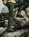 woman wearing deep forest tights with reinforced knees and Fjällräven logo climbing a rocky surface