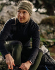 Woman sitting outdoors in a natural setting wearing outdoor gear.
