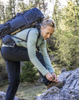 woman with a hiking backpack and tying her shoelace