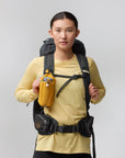 Person wearing a black backpack and yellow shirt on a gray background