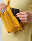 Person holding a yellow waist bag with a phone inside, wearing a yellow shirt.