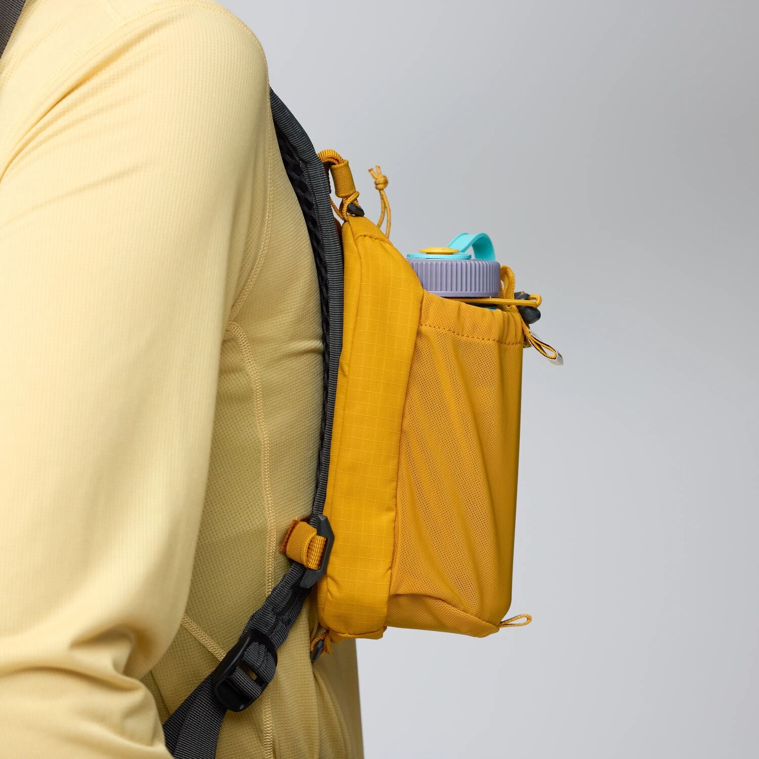 Yellow crossbody bag with a black strap on a light gray background