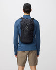 Person wearing a black backpack on a light gray background