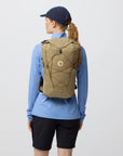 Person wearing a beige backpack with a Fjällräven on a plain background