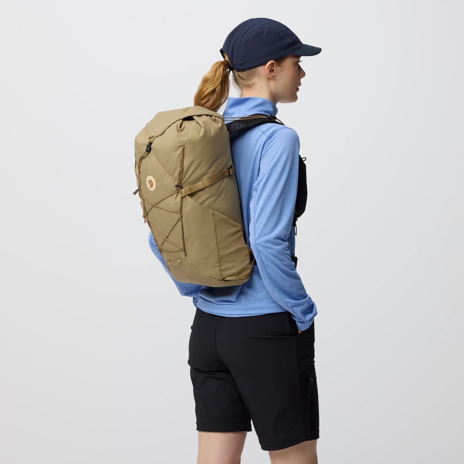 Person wearing a brown backpack on a plain background