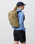 Person wearing a brown backpack on a plain background