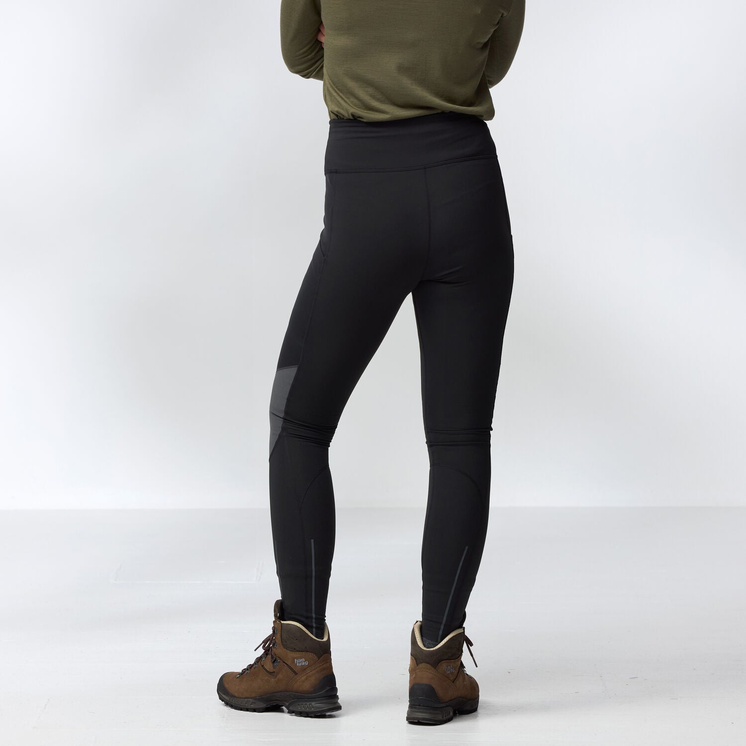 Person wearing black leggings tights and brown hiking boots on a white background