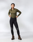 Woman wearing a green long-sleeve top and black leggings tights on a white background