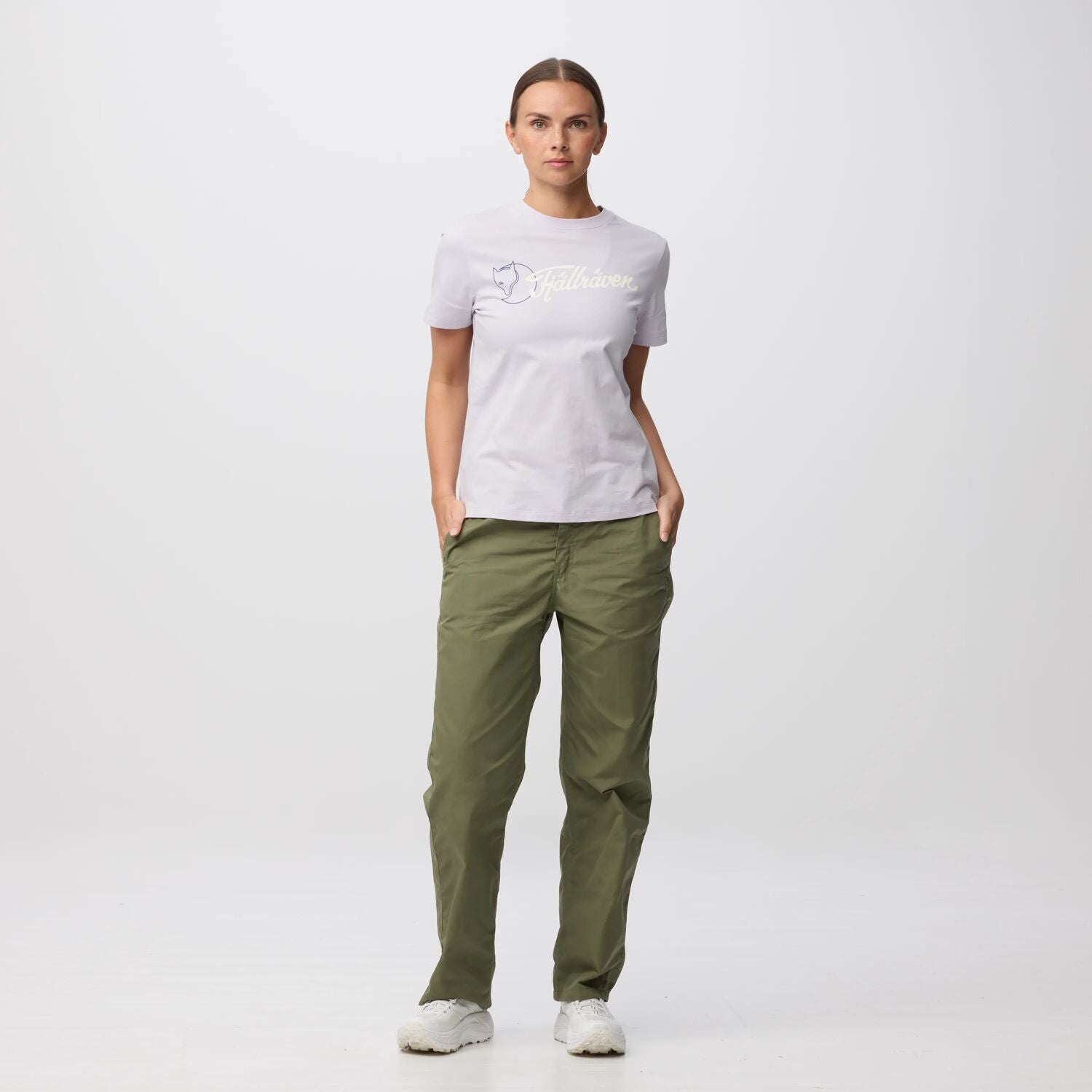 Person wearing a white t-shirt with a  fjallraven logo and green pants on a white background