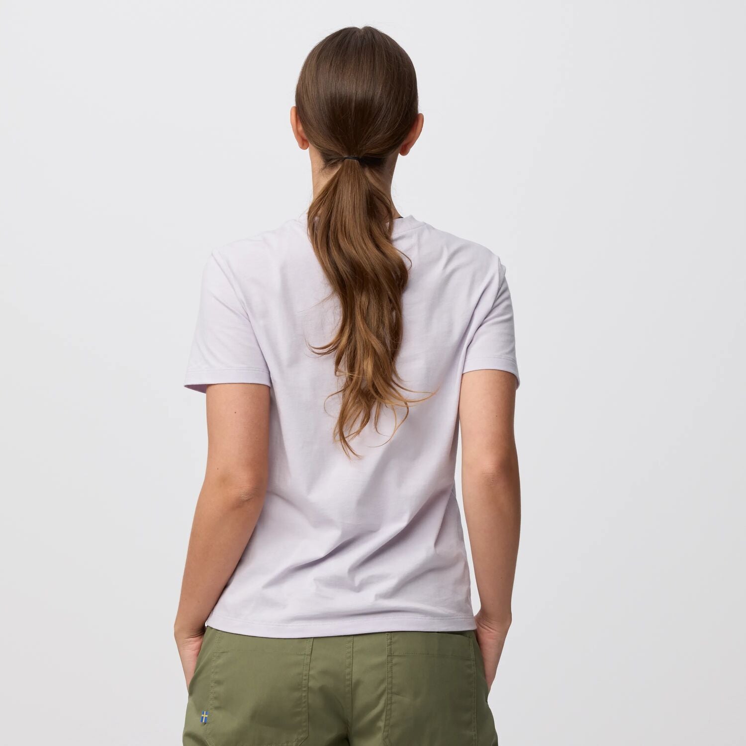Person wearing a white t-shirt and green pants on a light gray background
