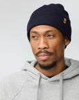 Man wearing a navy beanie and gray hoodie against a light gray background