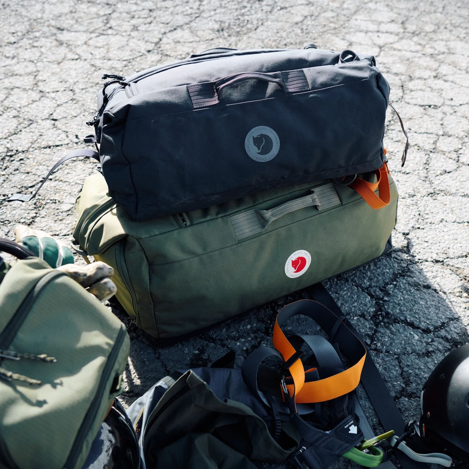 Two backpacks on a cracked asphalt surface with visible Fjällräven logos.
