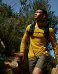 Man hiking on a trail with greenery and clear sky