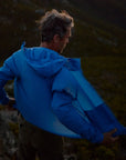 Person wearing a blue jacket standing on a rocky mountain