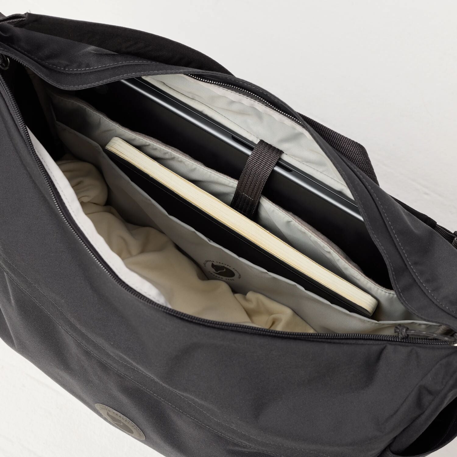 Black duffel bag with a laptop and clothes inside on a white background