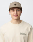 Person wearing a beige cap and t-shirt with arctic fox logo on a light gray background