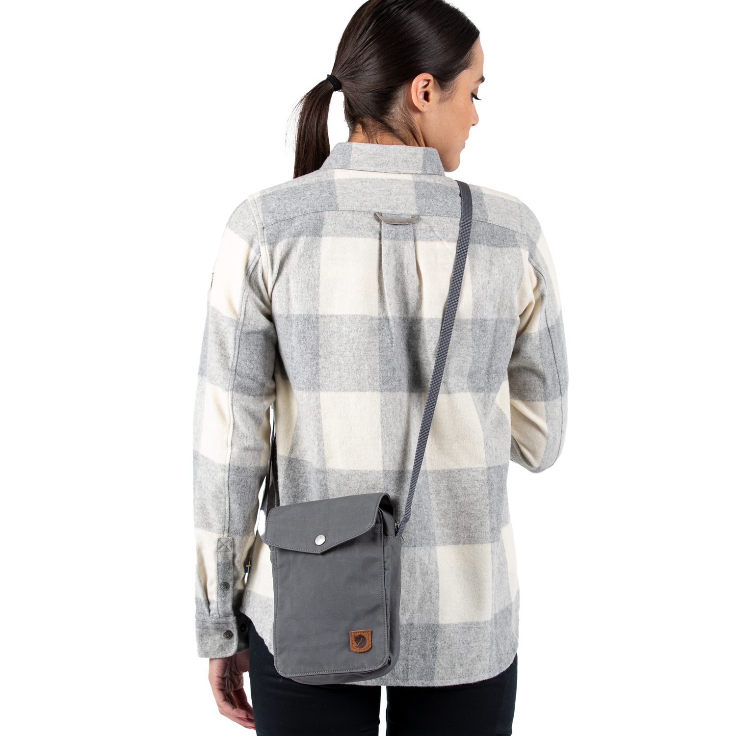 Woman wearing a plaid shirt with a gray crossbody bag on a white background